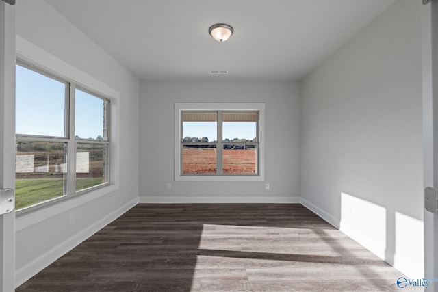 unfurnished room with visible vents, baseboards, and wood finished floors