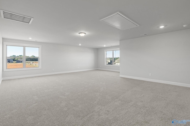 unfurnished room with visible vents, baseboards, attic access, and carpet floors