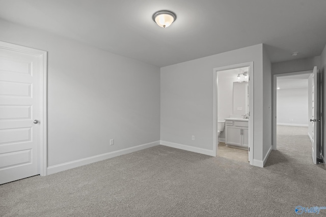 unfurnished bedroom with light carpet, baseboards, and connected bathroom