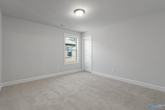 empty room featuring light colored carpet, baseboards, and visible vents