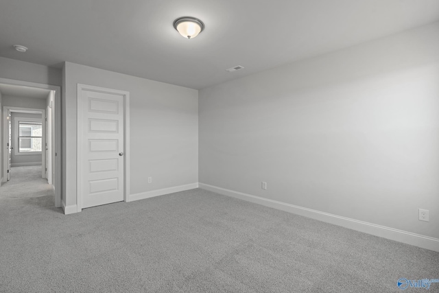 carpeted spare room with visible vents and baseboards