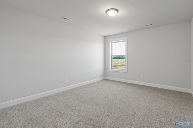 carpeted spare room featuring visible vents and baseboards