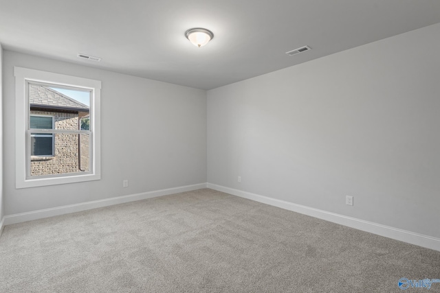 carpeted empty room featuring baseboards and visible vents