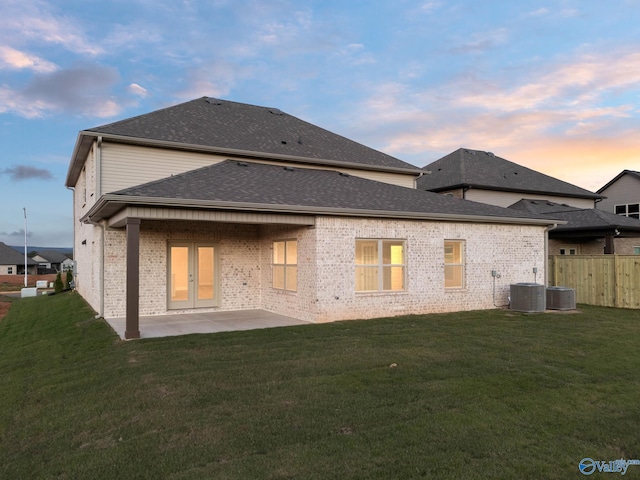 rear view of property featuring central air condition unit, french doors, a patio area, a yard, and fence