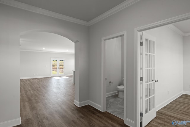 corridor featuring baseboards, arched walkways, dark wood finished floors, crown molding, and french doors