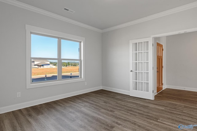 empty room featuring dark wood-type flooring, visible vents, baseboards, and ornamental molding