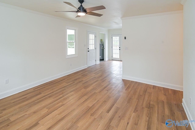 unfurnished room featuring a healthy amount of sunlight, ornamental molding, and light wood-type flooring