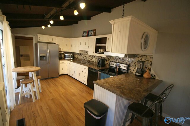 kitchen featuring a sink, appliances with stainless steel finishes, dark countertops, a peninsula, and backsplash