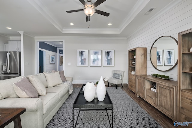 living room featuring crown molding, a tray ceiling, dark hardwood / wood-style flooring, and ceiling fan