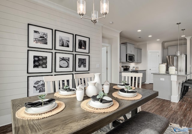 dining area featuring crown molding, wood walls, an inviting chandelier, and dark wood-type flooring