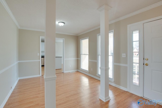 foyer entrance with crown molding, light wood finished floors, and ornate columns