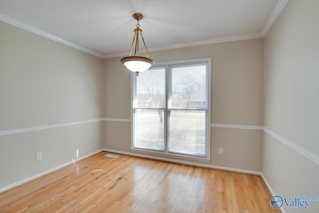 empty room with wood-type flooring, a textured ceiling, visible vents, and crown molding