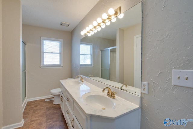 full bath with a textured wall, a stall shower, a sink, and baseboards