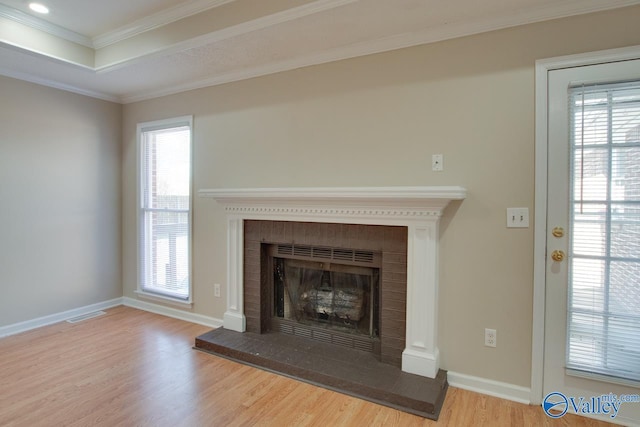 unfurnished living room featuring baseboards, visible vents, a fireplace with raised hearth, ornamental molding, and wood finished floors