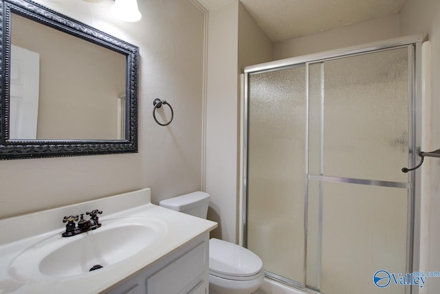 full bathroom with a stall shower, vanity, toilet, and a textured ceiling