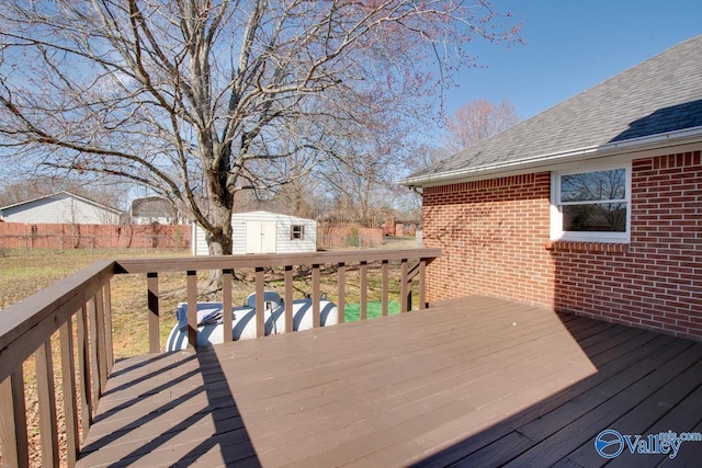 wooden terrace with a storage shed, an outbuilding, and fence