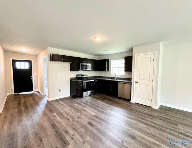 kitchen featuring baseboards, appliances with stainless steel finishes, a sink, and wood finished floors