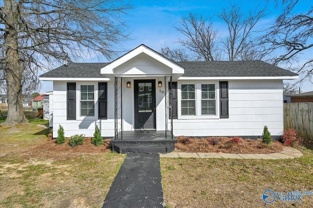 view of front of property with driveway, fence, and roof with shingles