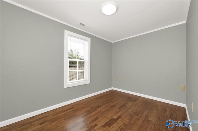 spare room featuring baseboards, visible vents, dark wood-type flooring, and crown molding