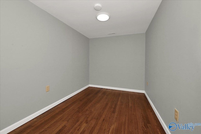 unfurnished room featuring dark wood finished floors, visible vents, and baseboards