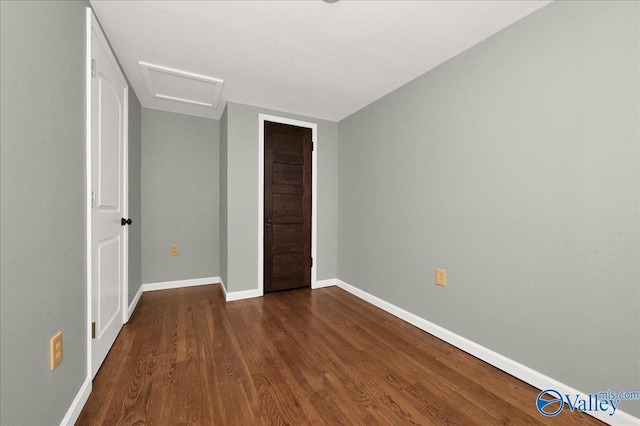 unfurnished bedroom with attic access, a closet, baseboards, and dark wood-style flooring