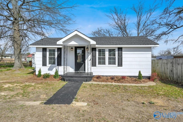 bungalow-style home with a shingled roof, fence, and aphalt driveway