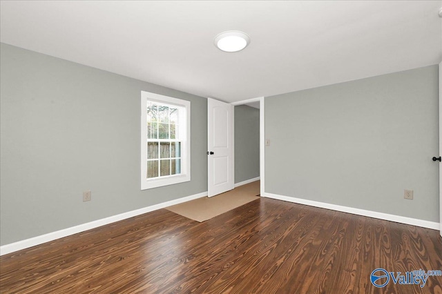 spare room featuring baseboards and wood finished floors