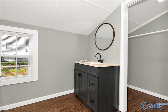bathroom with baseboards, vaulted ceiling, wood finished floors, and vanity