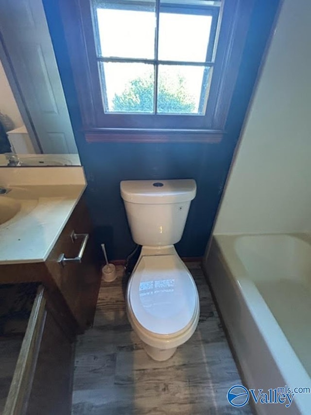 bathroom with toilet, a tub, and vanity