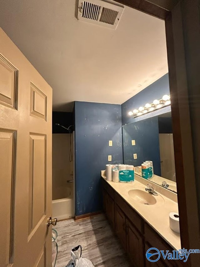 bathroom with hardwood / wood-style flooring,  shower combination, and vanity