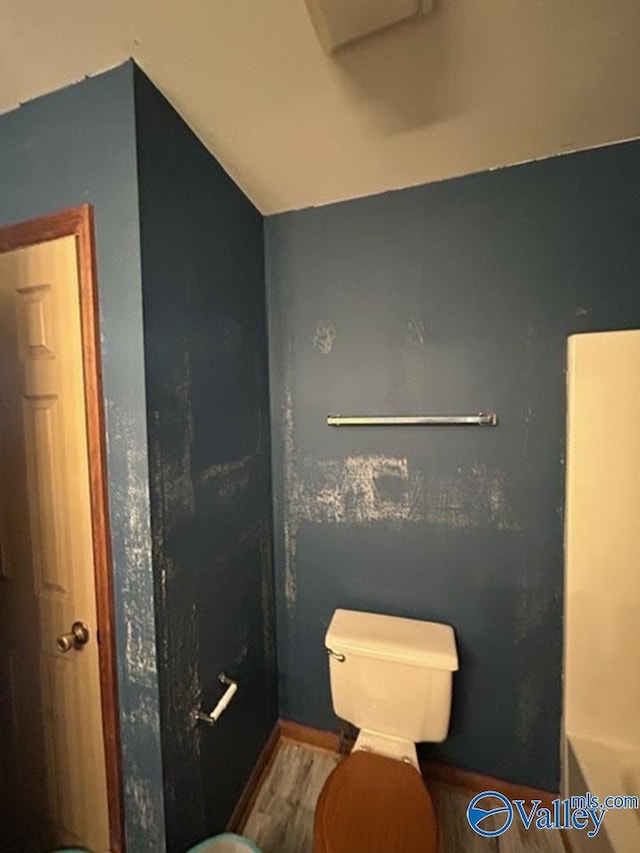 bathroom with lofted ceiling, hardwood / wood-style flooring, and toilet