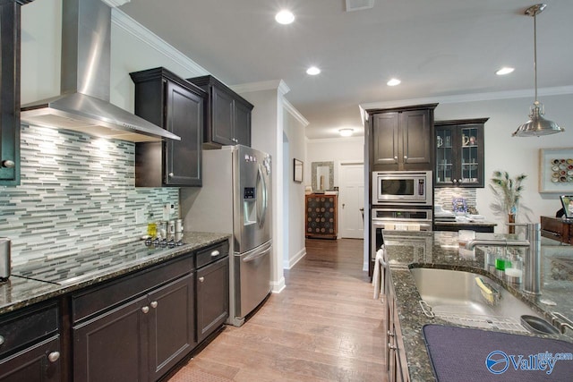 kitchen with wall chimney range hood, ornamental molding, pendant lighting, light hardwood / wood-style floors, and stainless steel appliances