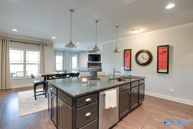 kitchen with stainless steel dishwasher, crown molding, hardwood / wood-style flooring, and dark stone countertops