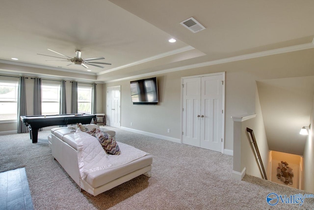 living room with crown molding, light carpet, a tray ceiling, and ceiling fan