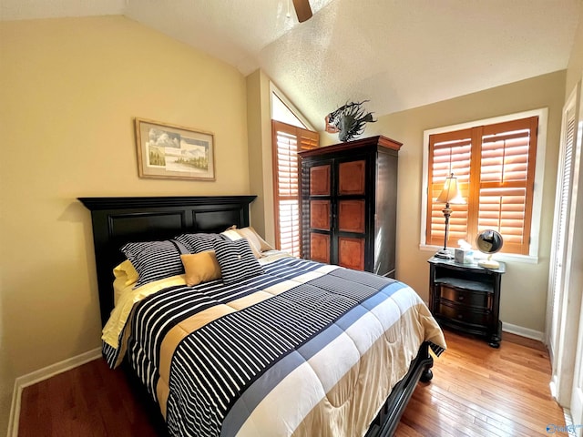 bedroom featuring lofted ceiling, ceiling fan, light hardwood / wood-style floors, and a textured ceiling