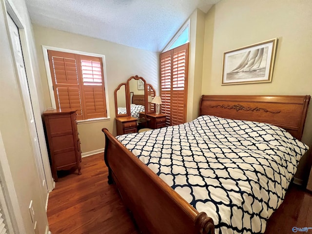 bedroom with a textured ceiling, vaulted ceiling, and dark hardwood / wood-style flooring