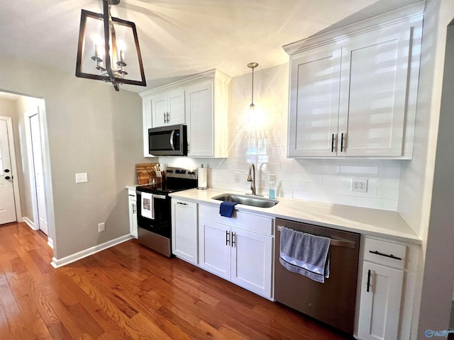 kitchen with dark hardwood / wood-style floors, stainless steel appliances, white cabinets, sink, and hanging light fixtures