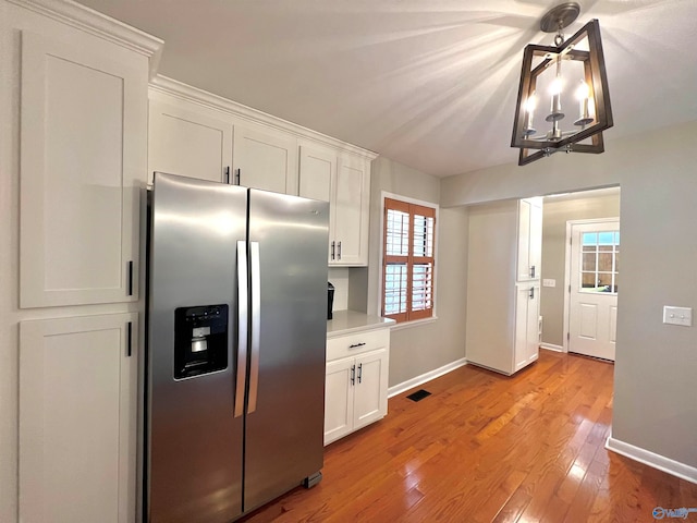 kitchen with a notable chandelier, white cabinetry, light hardwood / wood-style flooring, and stainless steel refrigerator with ice dispenser