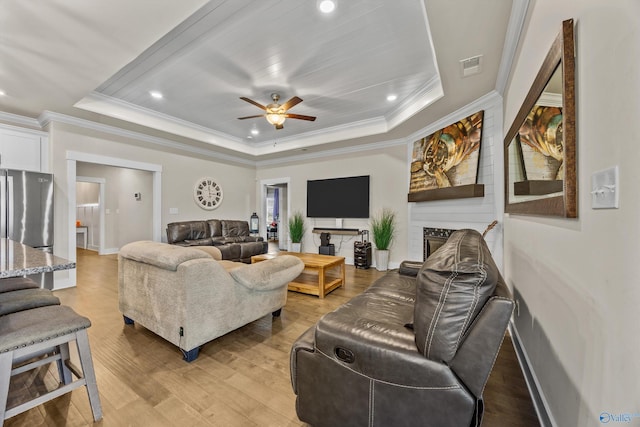22584 Big Oak Dr, Athens, AL 35613 - living room featuring a ceiling fan, ornamental molding, a tray ceiling, and light wood finished floors