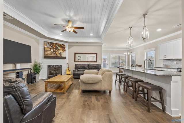 22584 Big Oak Dr, Athens, AL 35613 - living area with a tray ceiling, dark wood-style flooring, recessed lighting, ceiling fan with notable chandelier, and crown molding