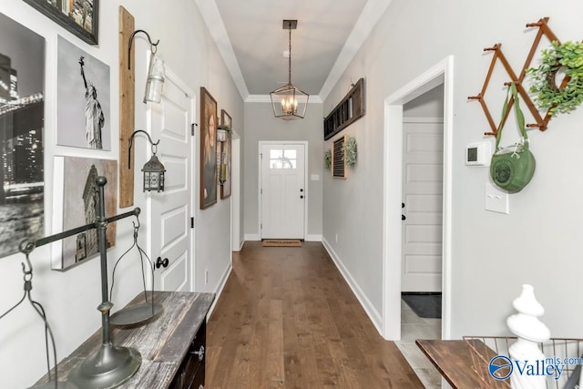 doorway with an inviting chandelier, baseboards, ornamental molding, and dark wood finished floors