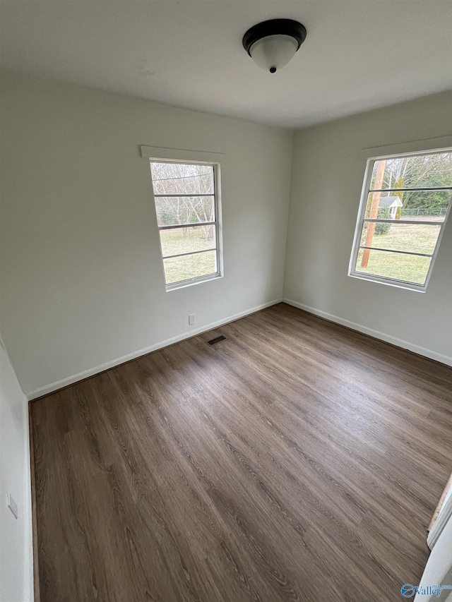 unfurnished room with plenty of natural light and dark hardwood / wood-style floors