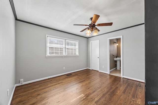 unfurnished bedroom with ceiling fan, dark hardwood / wood-style flooring, ensuite bathroom, a textured ceiling, and ornamental molding