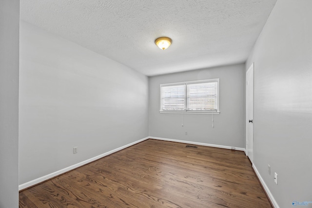 spare room featuring a textured ceiling and dark wood-type flooring