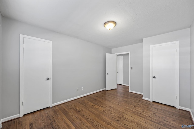 unfurnished bedroom with a textured ceiling and dark wood-type flooring