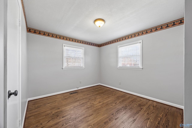 unfurnished room featuring hardwood / wood-style flooring, a textured ceiling, and a wealth of natural light