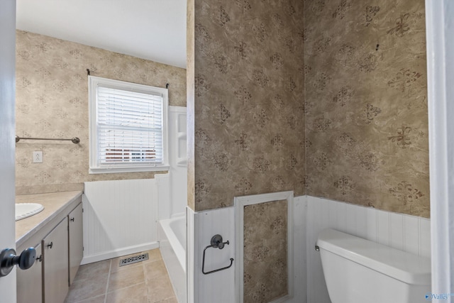 bathroom featuring a bathing tub, vanity, toilet, and tile patterned flooring