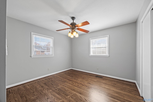 empty room with ceiling fan and dark hardwood / wood-style flooring