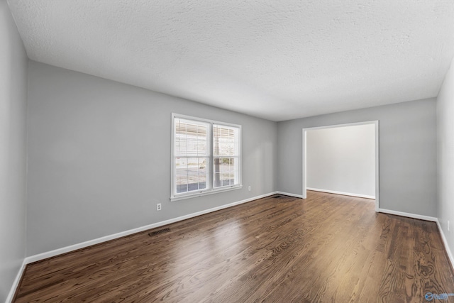 unfurnished room featuring a textured ceiling and dark hardwood / wood-style floors