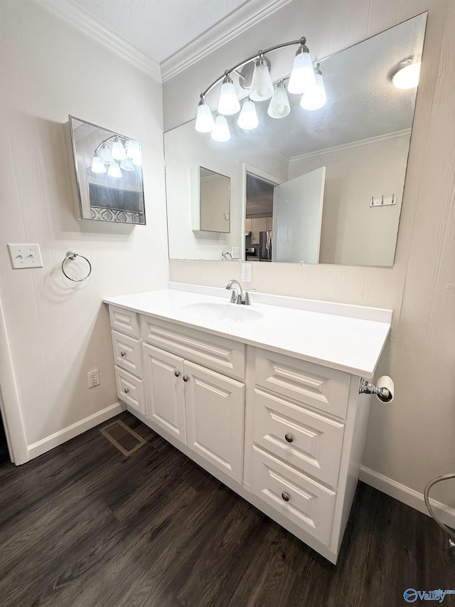 bathroom with wood-type flooring, vanity, a textured ceiling, and crown molding